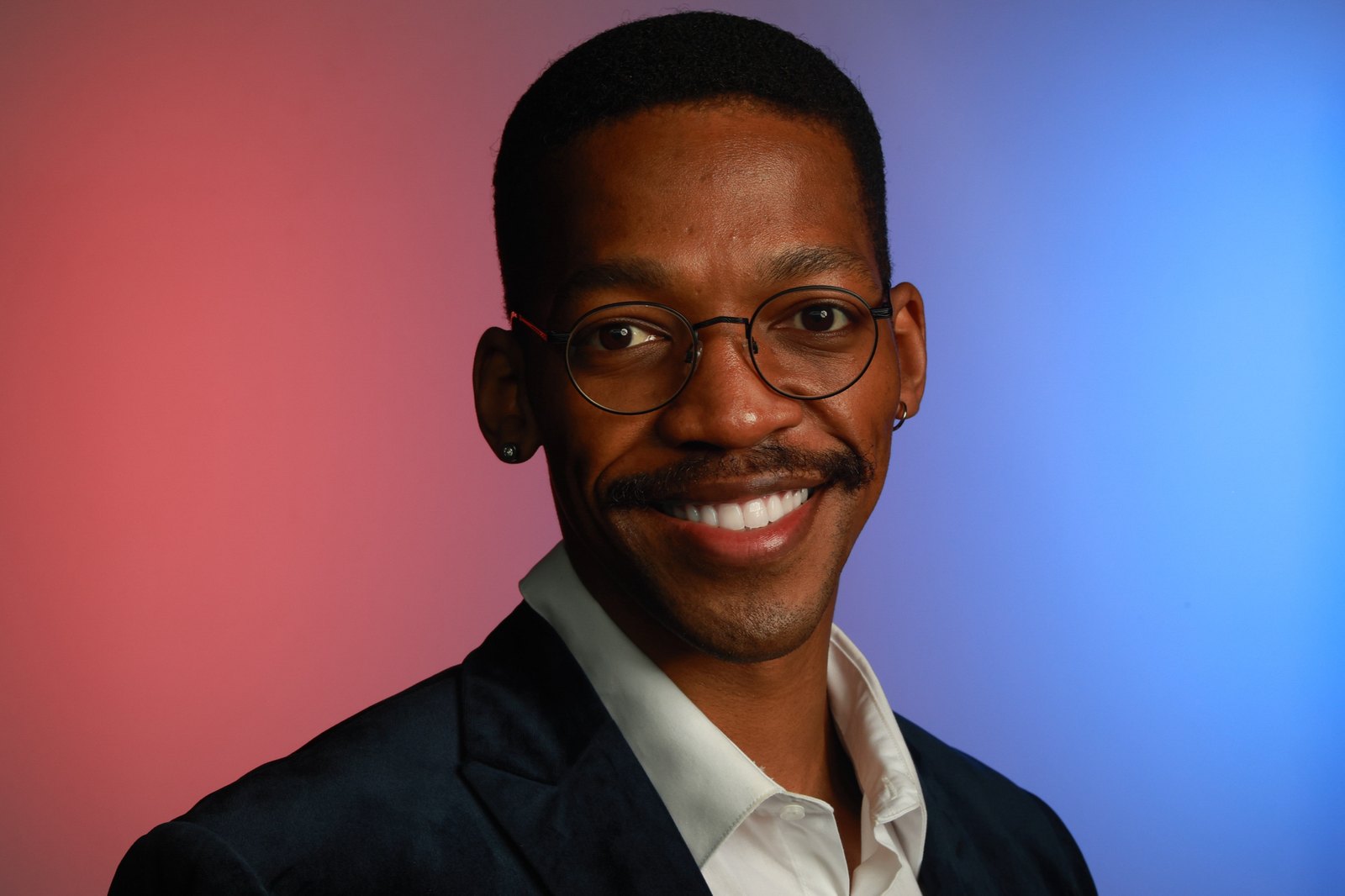 Professional headshot against a pink and blue color gradient background